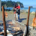 Below, Margarita Guerrero prepares baked salmon, in the traditional way, while James Island stands boldly across the Quillayute River during the Quileute Days celebration. 
Photo by Lonnie Archibald
