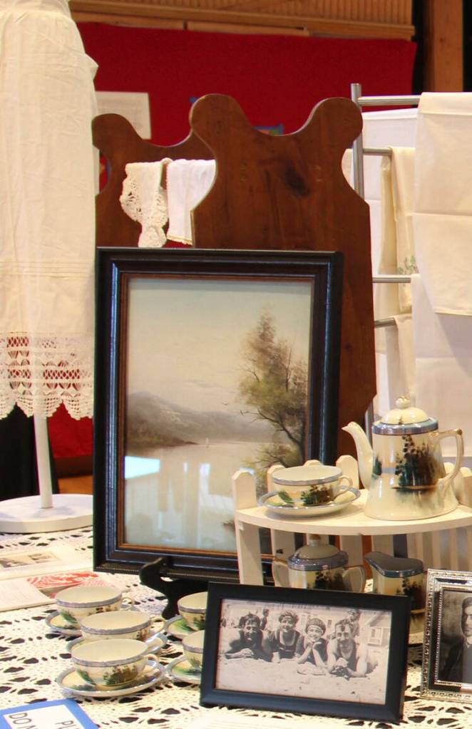 A vintage Norwegian Bunad apron once worn by Pastor Pam Hunters ancestor can be seen on the left; a vintage tea set and photos were displayed by Linda Keen.