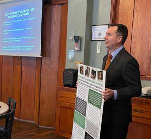 Nichols holds a sample of the posters that will be placed around county properties, advising potential trafficking victims of what they can do. Photo Christi Baron