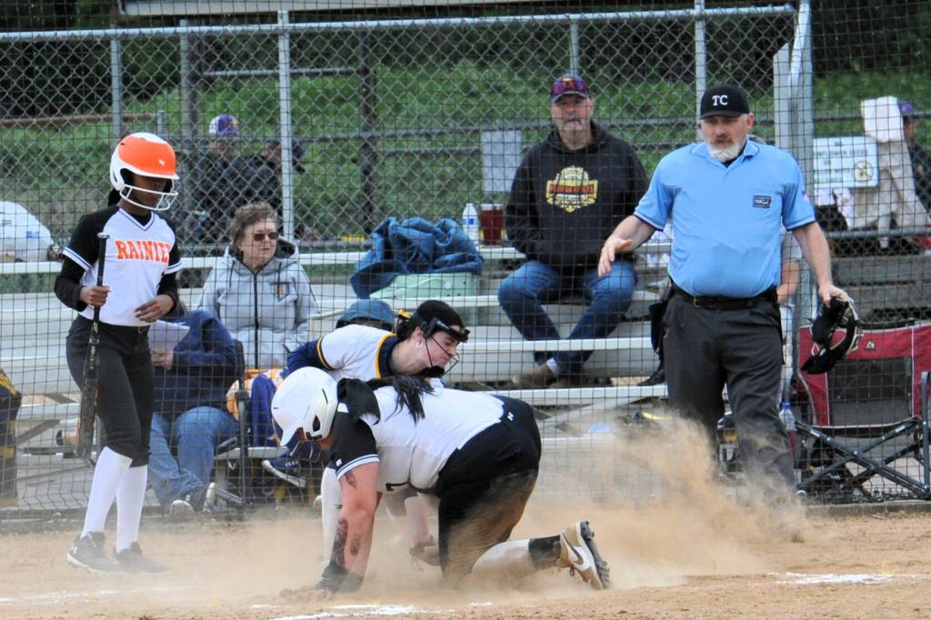 Rainiers Gracie Lantz beats the throw to home plate, where Forks pitcher Chloe Gaydeski makes the play in a cloud of dust.