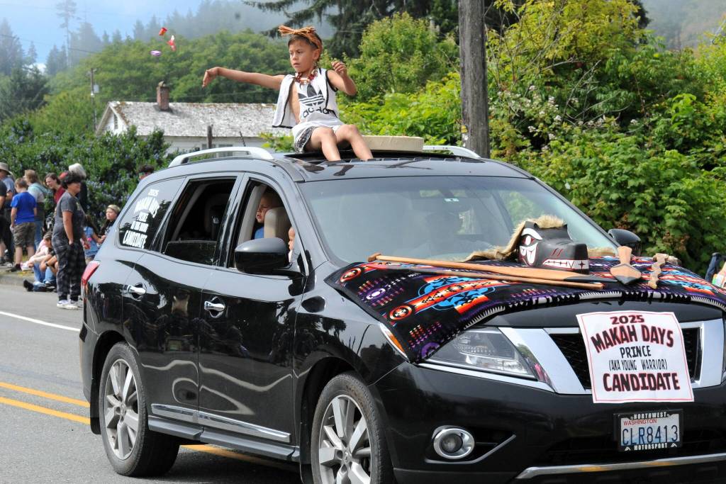 Makah Days 2025 Prince candidate, Danniel Corpuz, throws out candy during the parade.