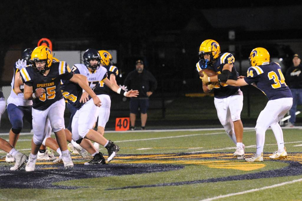 Tannon Gaydeski (34) hands off to running back Kaden Ward (23) while Mario Reyes (65) blocks.