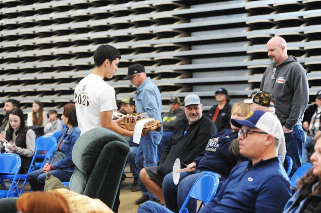 Photo Lonnie Archibald 
Noah Foster shows an item being auctioned to the crowd who gathered at the Forks High School Commons Saturday for the annual Quillayute Valley Scholarship Auction.