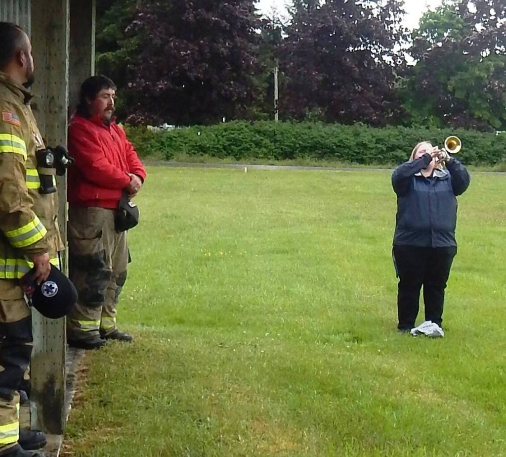 Photo Christi Baron 
Volunteer firemen look on as Meg Rasmussen offered taps at the end of the Memorial Day Ceremony.