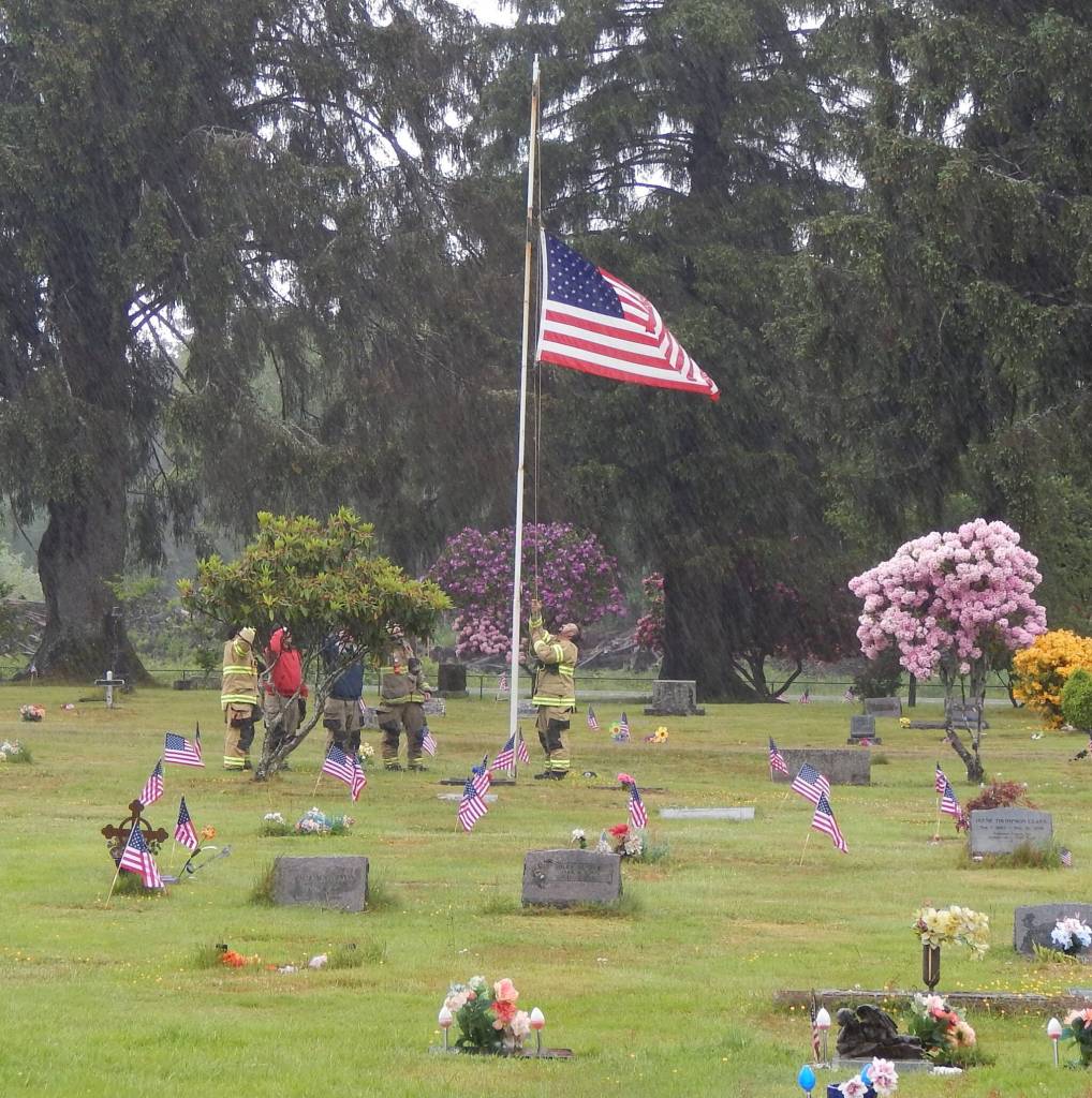Photo Christi Baron 
CCFD#1 members lower the American flag at the Forks Cemetery before the beginning of the service held on Monday.