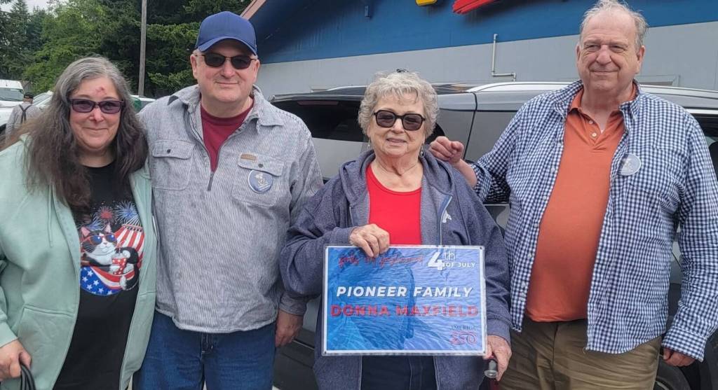 Donna Maxfield Hansen (holding the sign) was honored as the Parade Pioneer representing the Maxfield family. She was joined by her children, Donita Wakefield and Brad Parker (on the left), and were escorted through the parade by Judge Bruce Hanify on the right. Photo Christi Baron