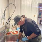 Food Bank President Warren Johnson and a volunteer portion up fresh fish donated by the Pacific Coast Salmon Coaliton early Monday morning.